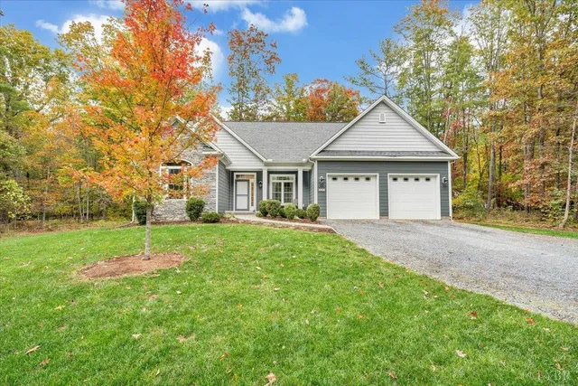 a view of a house with a yard and large tree
