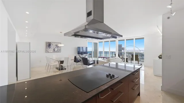 a view of a room with kitchen island stainless steel appliances wooden floor dining table and chairs