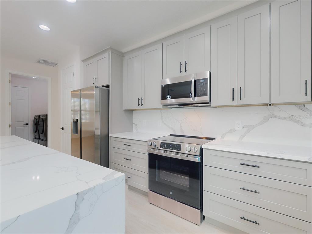 12222 Southwest 95th Place Dunnellon, FL 34432 - Photo 19 of 23 a kitchen with stainless steel appliances white cabinets and a stove a refrigerator with wooden floor