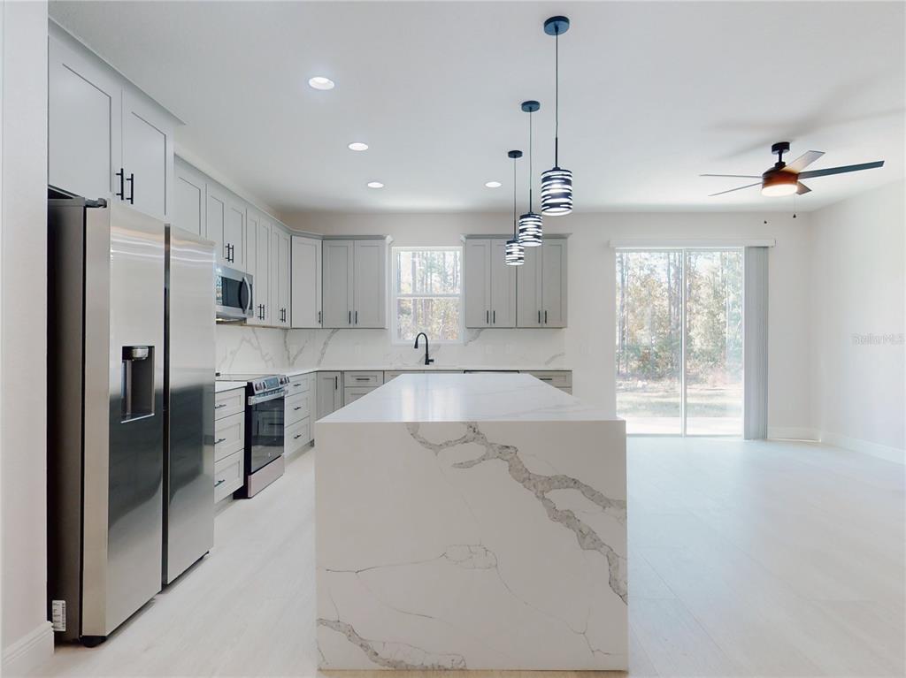 12222 Southwest 95th Place Dunnellon, FL 34432 - Photo 6 of 23 a large kitchen with kitchen island a large counter top space stainless steel appliances and a chandelier