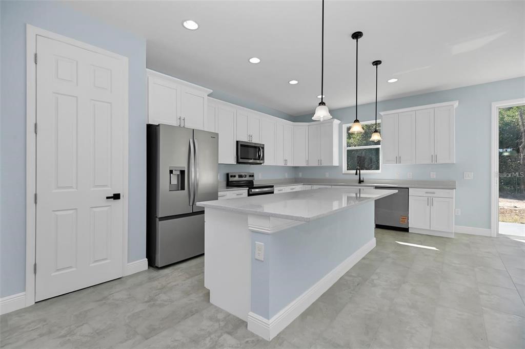 12222 Southwest 95th Place Dunnellon, FL 34432 - Photo 8 of 17 a kitchen with white cabinets and stainless steel appliances