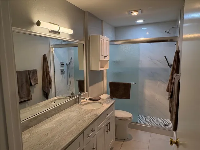 a bathroom with a granite countertop sink toilet and shower