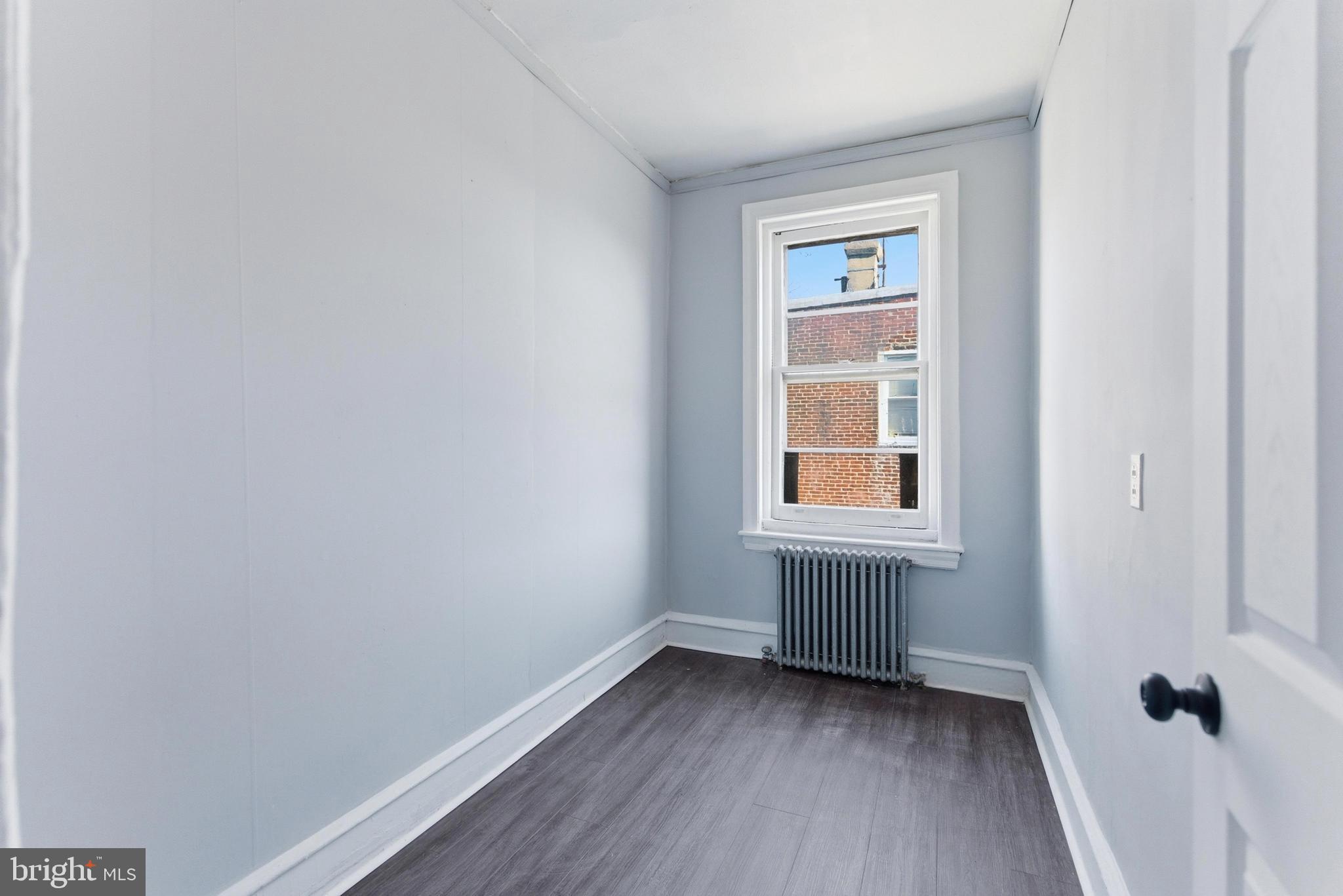 7233 West Chester Pike Upper Darby, PA 19082 - Photo 13 of 14 a view of an empty room with wooden floor and a window