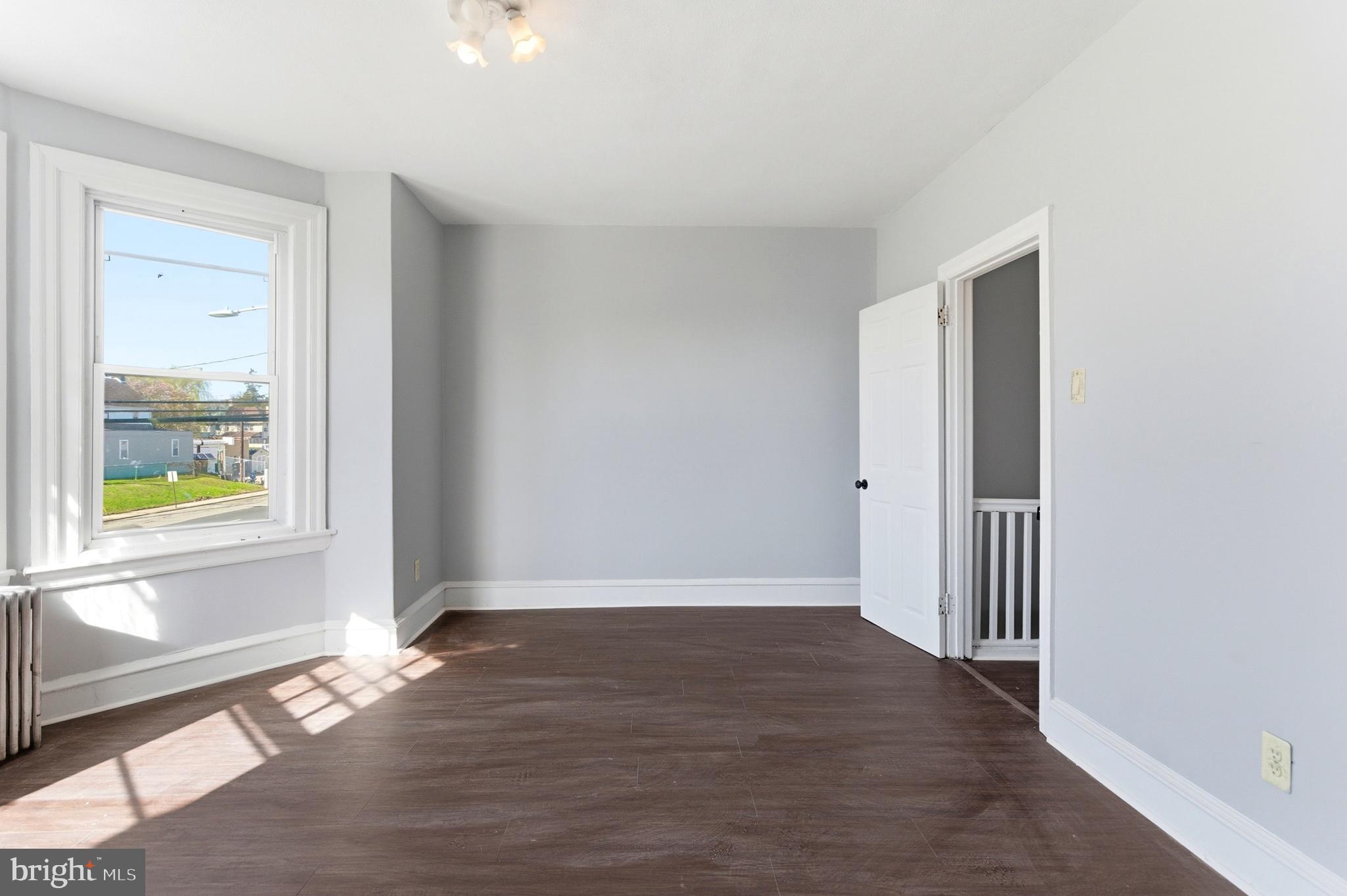 7233 West Chester Pike Upper Darby, PA 19082 - Photo 9 of 14 a view of an empty room with wooden floor and a window