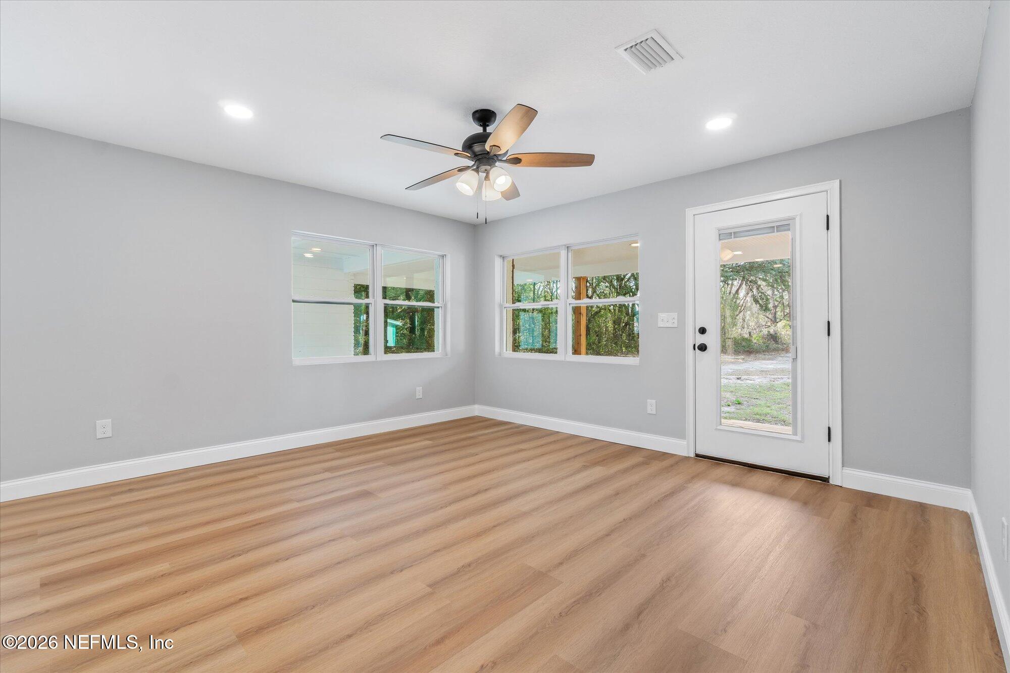 102 Mullins Road Interlachen, FL 32148 - Photo 15 of 45 an empty room with wooden floor ceiling fan and windows