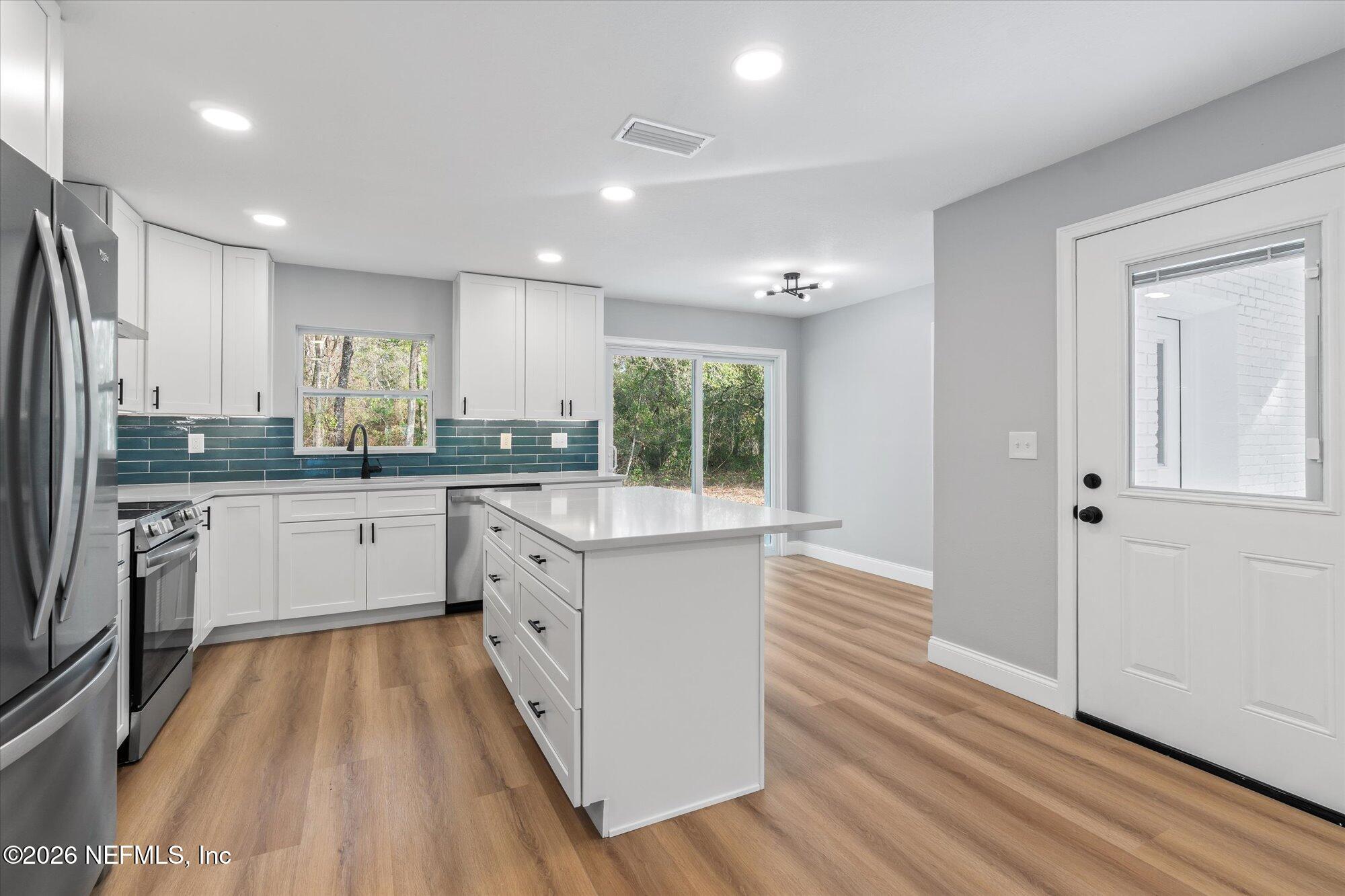 102 Mullins Road Interlachen, FL 32148 - Photo 9 of 45 a kitchen with wooden floors stainless steel appliances a sink and a window