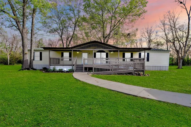 a front view of a house with a garden and trees