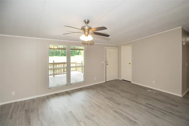 an empty room with wooden floor fan and windows