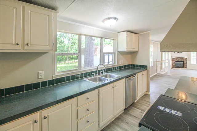 a kitchen with granite countertop a sink a window and cabinets