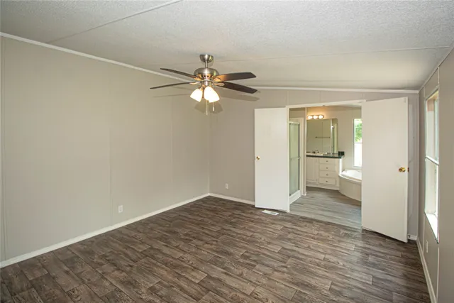 an empty room with wooden floor and fan