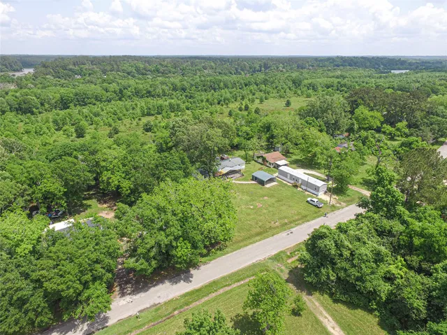 an aerial view of residential houses with outdoor space and trees all around