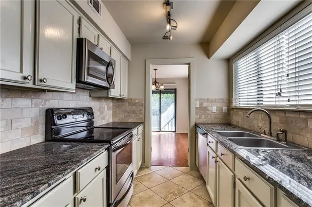 a kitchen with stainless steel appliances granite countertop a sink stove and cabinets
