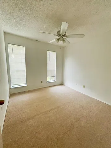 an empty room with a window and a ceiling fan