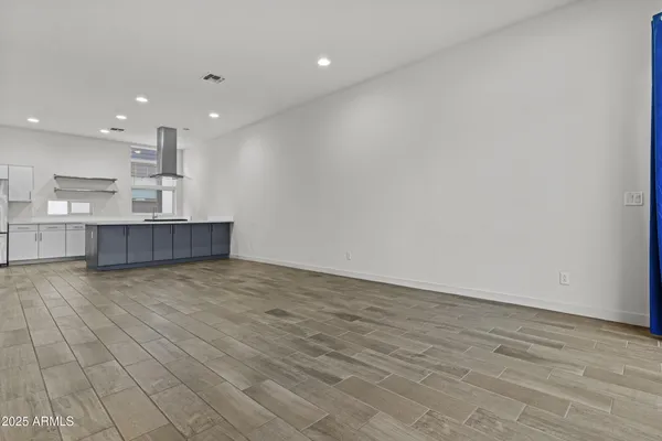 an empty room with kitchen and natural light