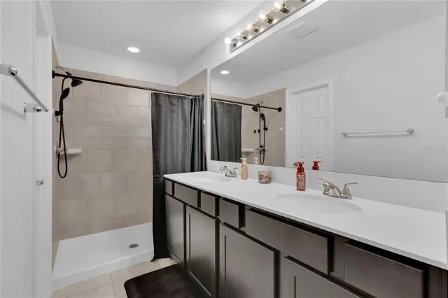 a bathroom with a shower sink vanity and mirror