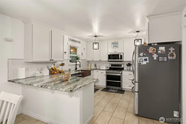 a kitchen with stainless steel appliances granite countertop a stove top oven a refrigerator and white cabinets
