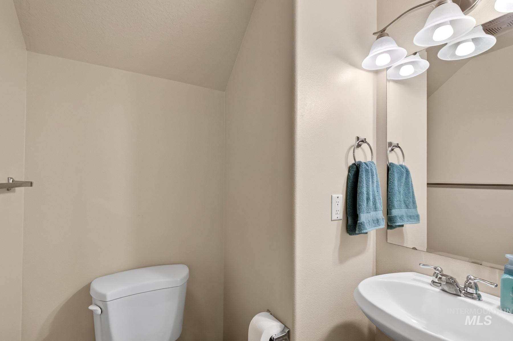 5020 Northrup Way Caldwell, ID 83607 - Photo 18 of 36 White pedestal sink with chrome fixtures, an overhead vanity light with four frosted glass shades, and a wall-mounted mirror