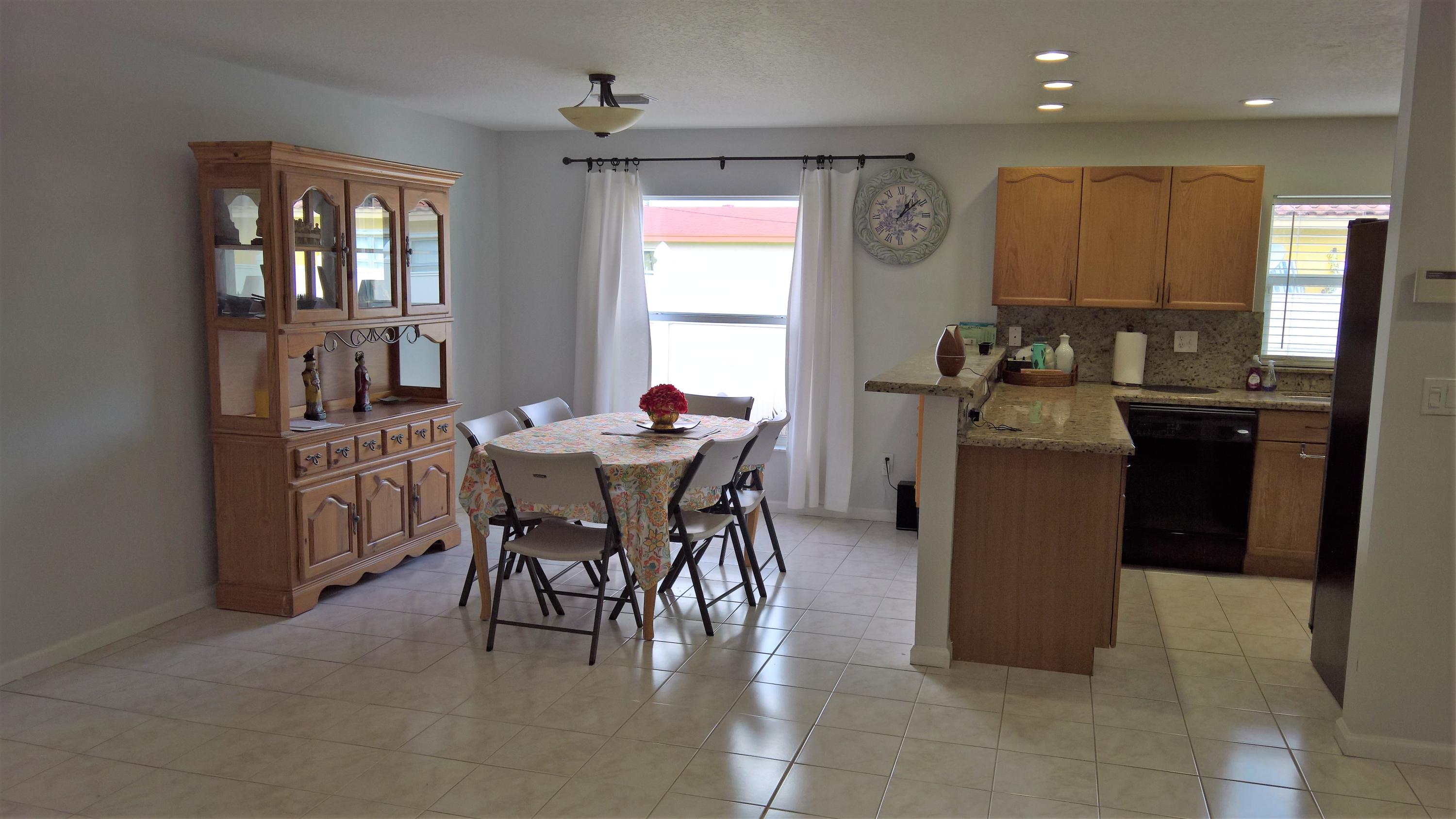 15035 Jackson Road Delray Beach, FL 33484 - Photo 3 of 17 a kitchen with a dining table chairs and refrigerator