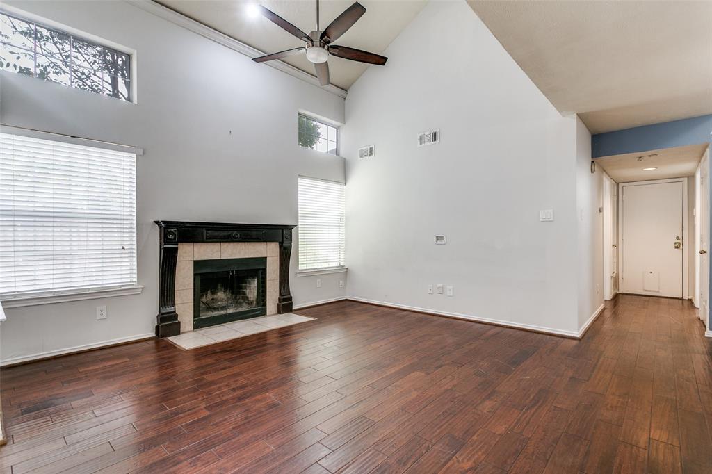 9416 Penny Lane Irving, TX 75063 - Photo 5 of 21 an empty room with wooden floor a fireplace a ceiling fan and windows