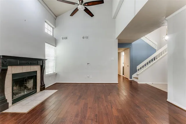 a view of an empty room with wooden floor fireplace and a window