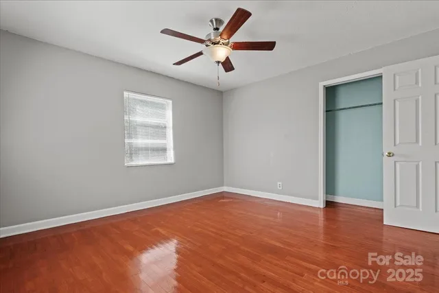 an empty room with wooden floor and ceiling fan