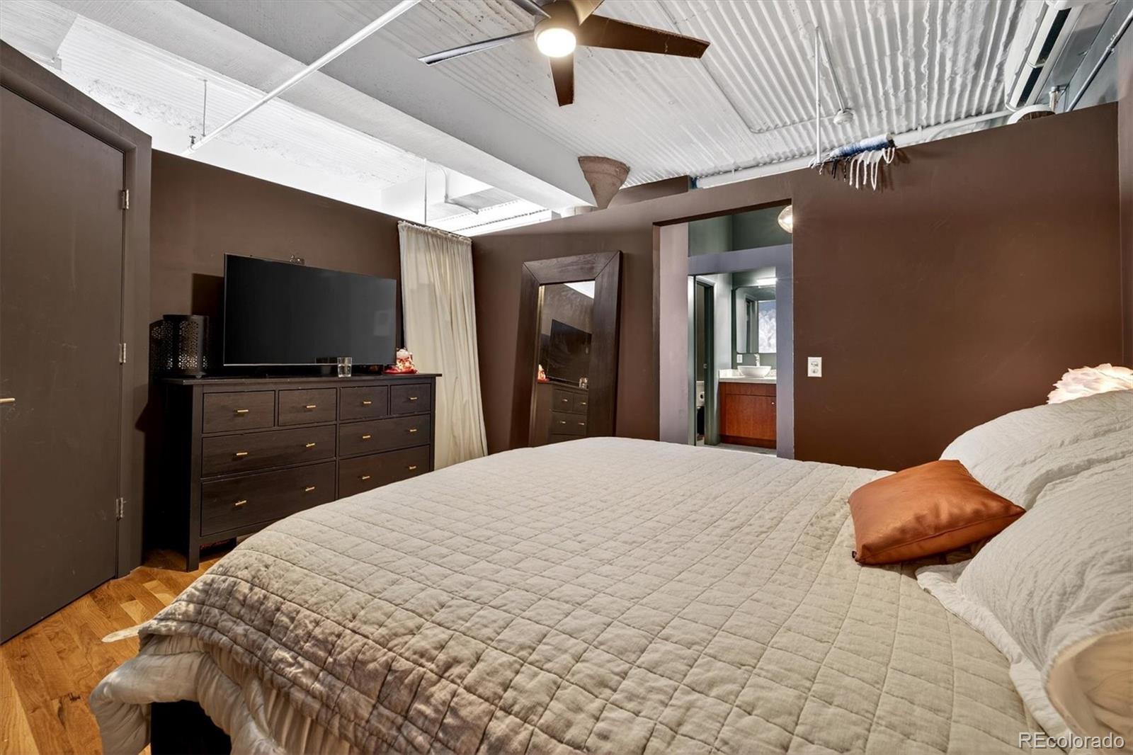 2261 Blake Street, Unit 4F Denver, CO 80205 - Photo 20 of 38 a bedroom with a bed and a flat tv screen on dresser