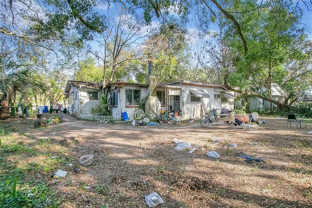 a view of a house with a yard and large trees