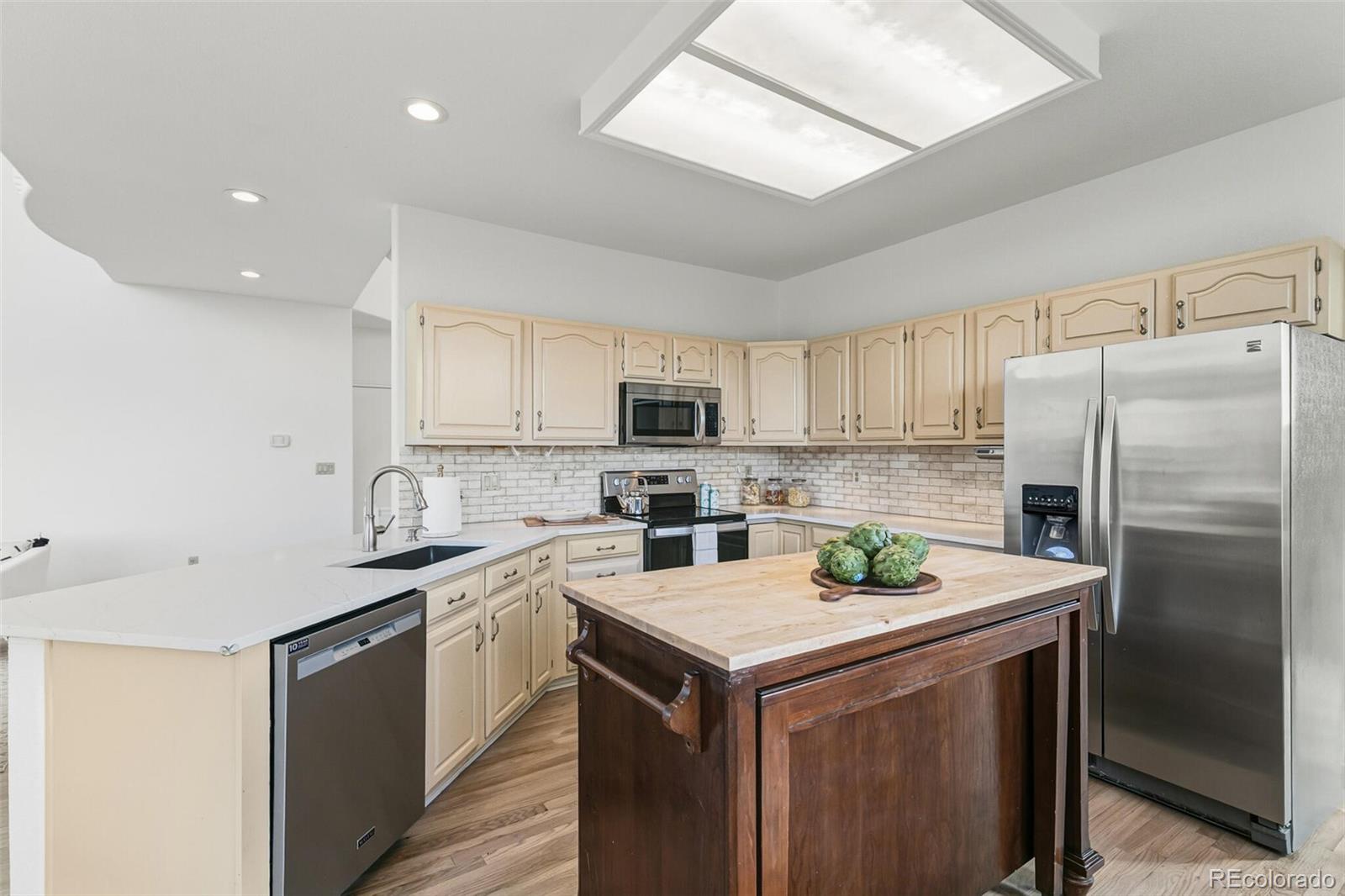 10275 Baneberry Place Highlands Ranch, CO 80129 - Photo 11 of 50 a kitchen with a sink a stove a refrigerator and white cabinets