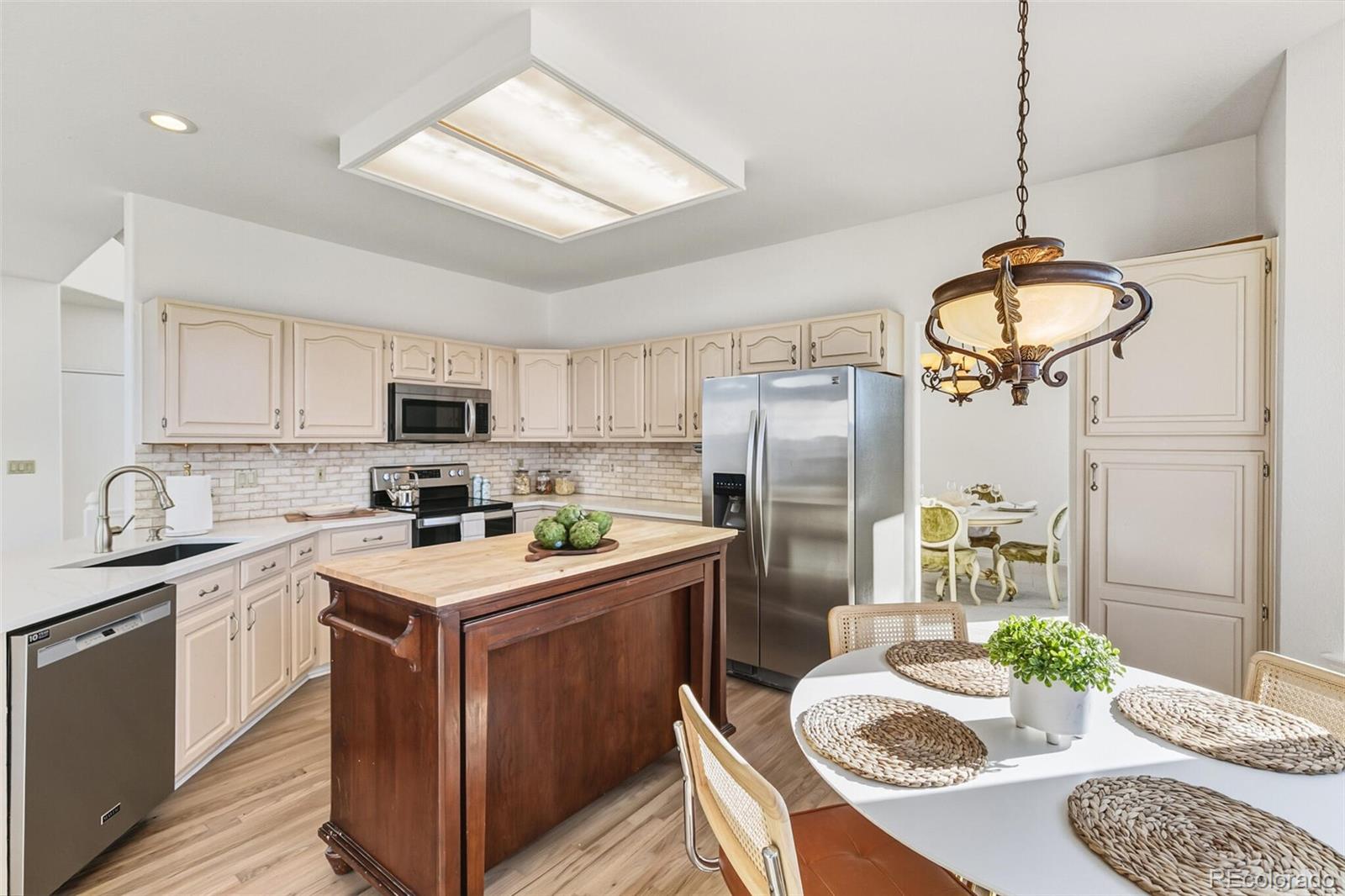 10275 Baneberry Place Highlands Ranch, CO 80129 - Photo 12 of 50 a kitchen with stainless steel appliances granite countertop a sink a stove a refrigerator cabinets a dining table and chairs