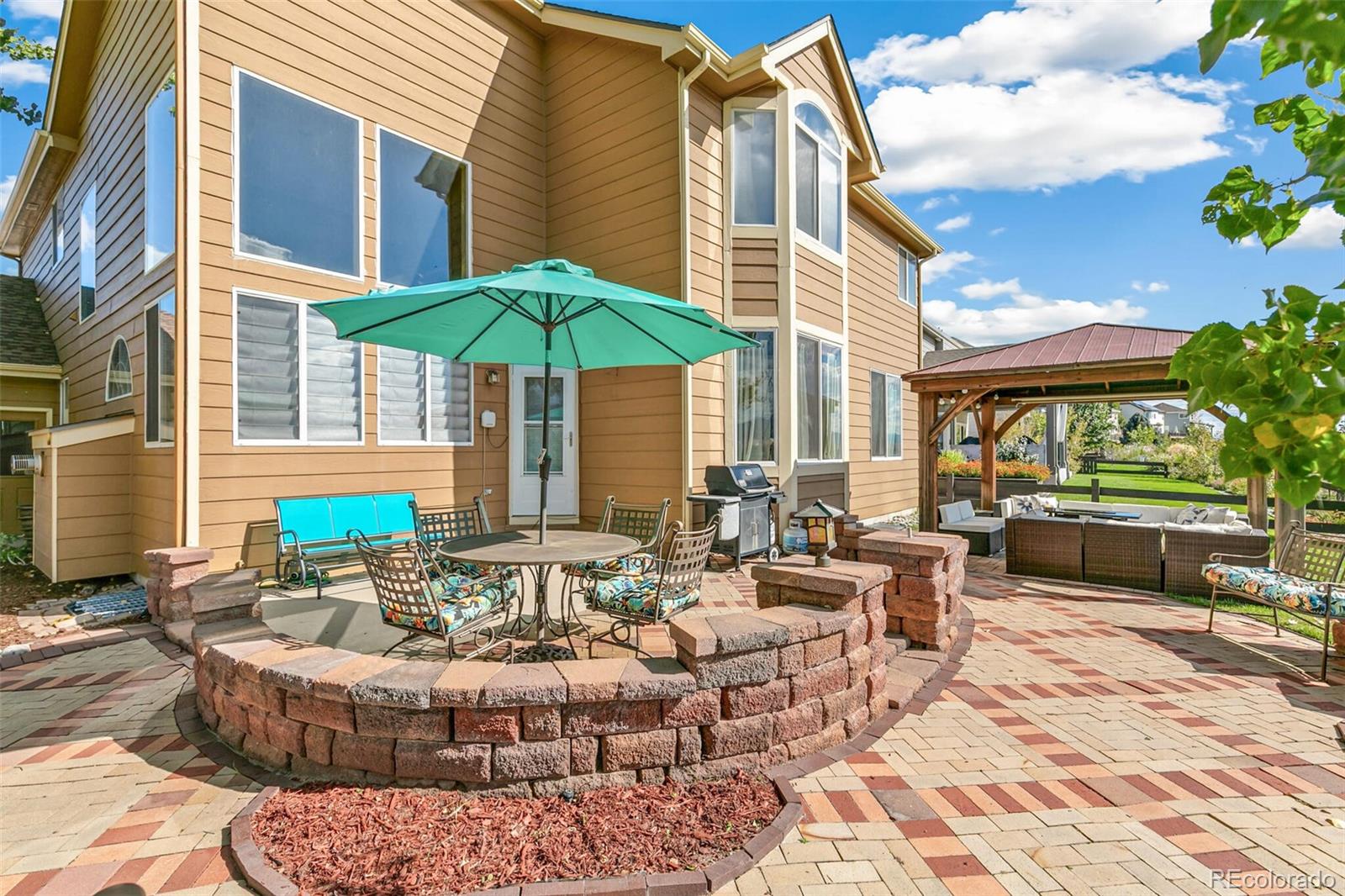 10275 Baneberry Place Highlands Ranch, CO 80129 - Photo 36 of 50 a view of a patio with couches table and chairs under an umbrella with a barbeque