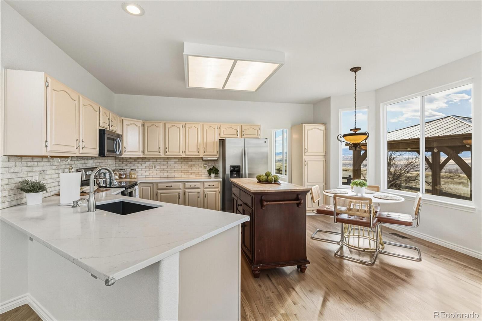 10275 Baneberry Place Highlands Ranch, CO 80129 - Photo 10 of 50 a kitchen with a stove a sink dishwasher a refrigerator and white cabinets with wooden floor