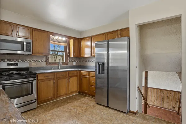 a kitchen with stainless steel appliances granite countertop a refrigerator stove and sink