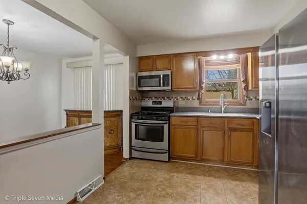 a kitchen with stainless steel appliances granite countertop a refrigerator a stove top oven a sink and dishwasher