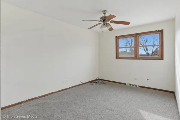 an empty room with windows and fan