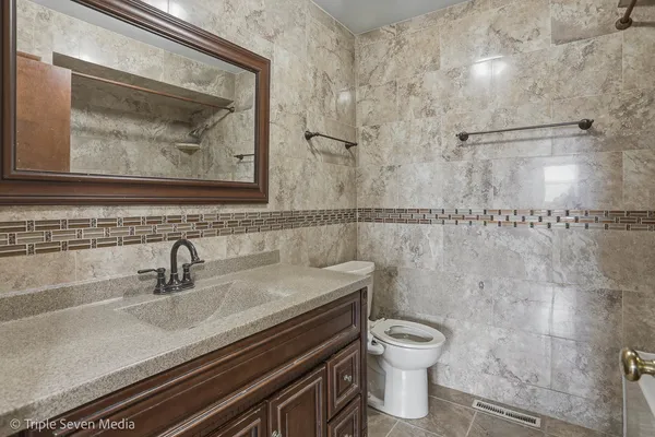 a bathroom with a granite countertop sink a toilet and a shower