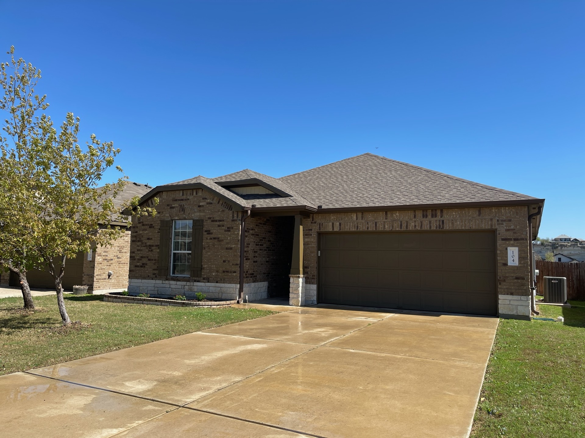 View of front of home with brick siding, an attached garage, driveway, roof with shingles, and a front yard