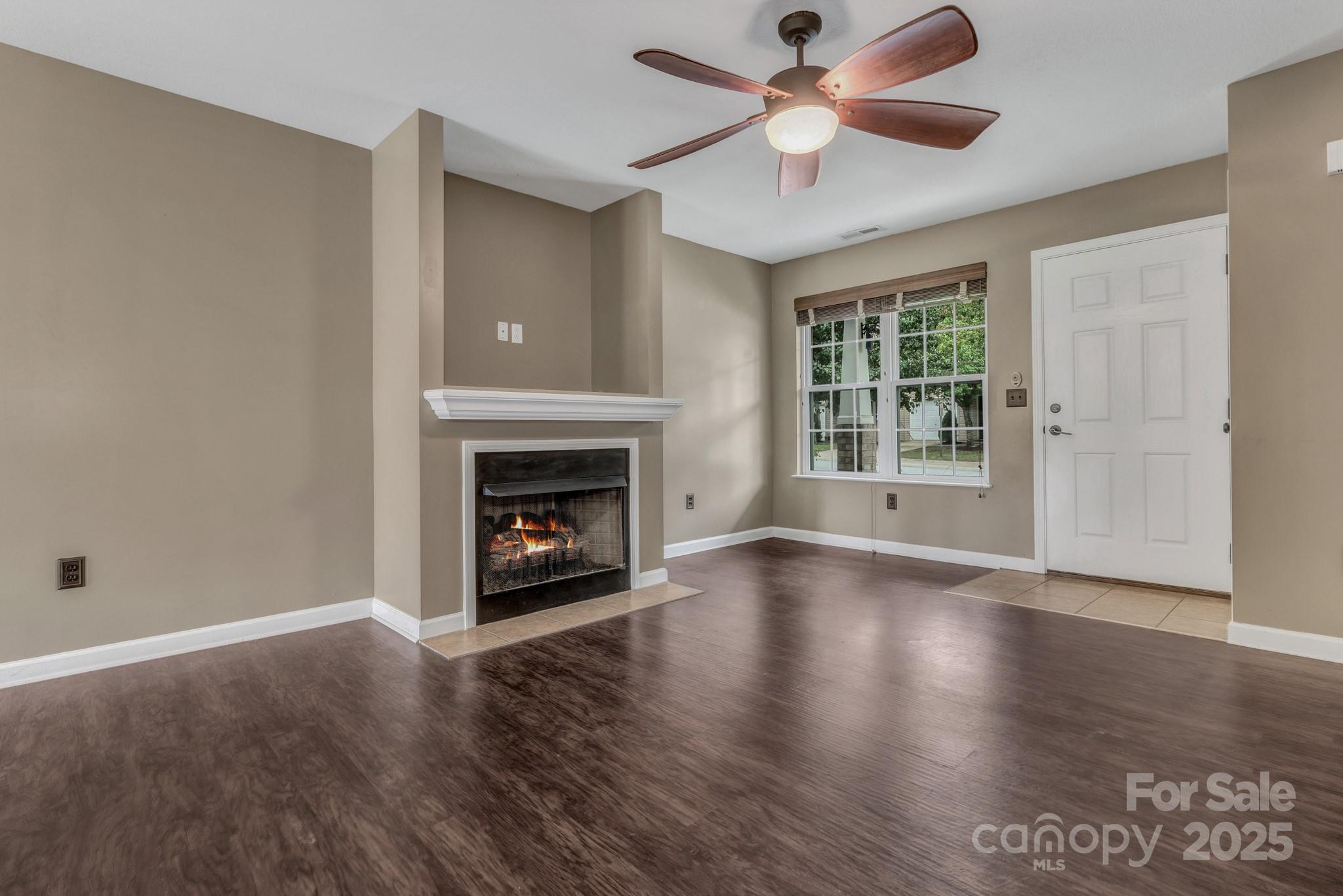 4 Lilac Fields Way Arden, NC 28704 - Photo 10 of 33 an empty room with wooden floor a fireplace a ceiling fan and windows