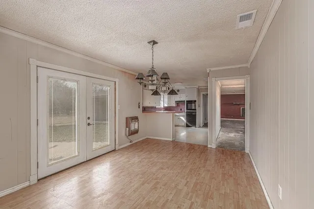 an empty room with a chandelier fan and windows