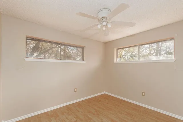 a view of an empty room with window and wooden floor