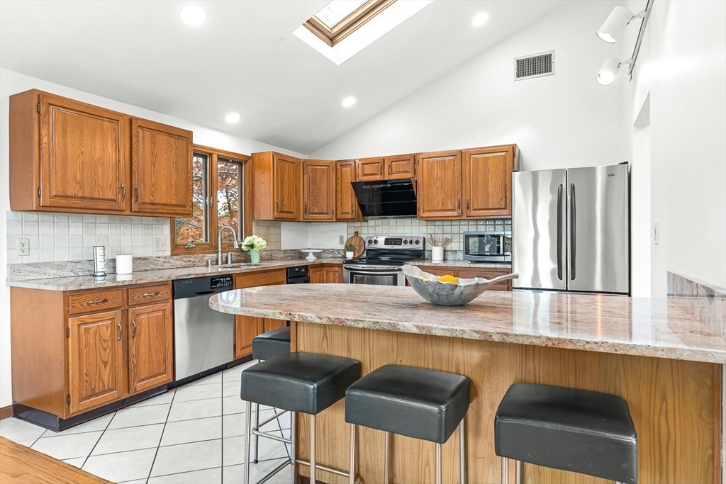 25 Murdoch Road Stoneham, MA 02180 - Photo 9 of 39 a kitchen with stainless steel appliances granite countertop a stove top oven a sink a refrigerator and cabinets