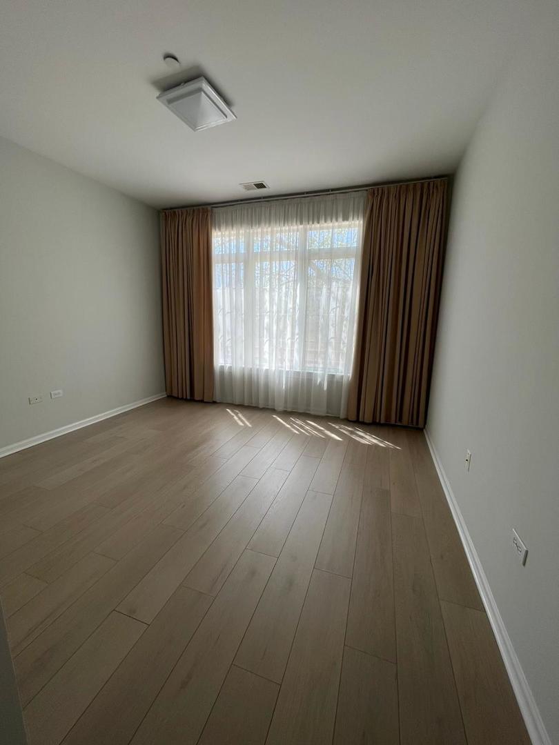 660 McHenry Road, Unit 107 Wheeling, IL 60090 - Photo 15 of 24 an empty room with wooden floor and windows