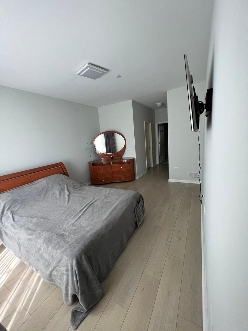 660 McHenry Road, Unit 107 Wheeling, IL 60090 - Photo 17 of 24 a bedroom with furniture and a wooden floor