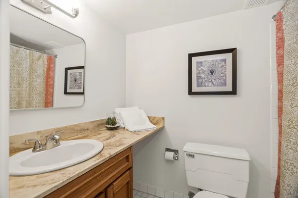 a bathroom with a granite countertop toilet a sink and a mirror