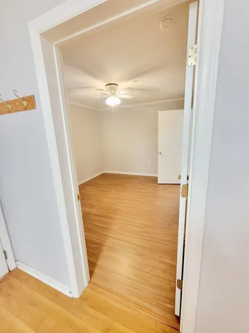an empty room with a ceiling fan and wooden floor