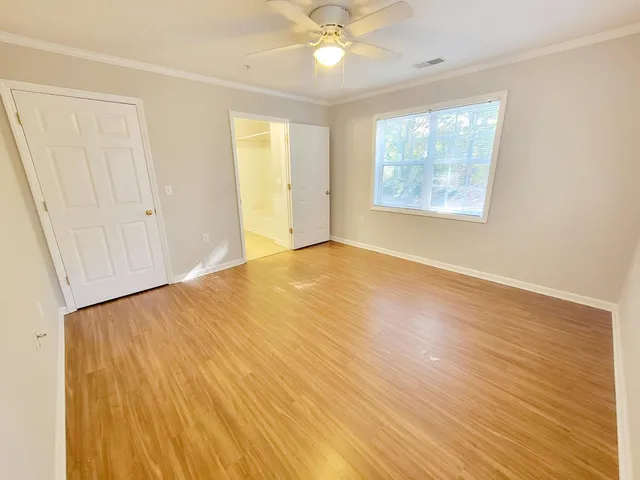 a view of empty room with wooden floor and fan