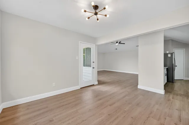 an empty room with wooden floor ceiling fan and window