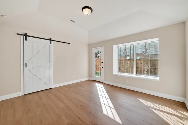 a view of an empty room with wooden floor and a window