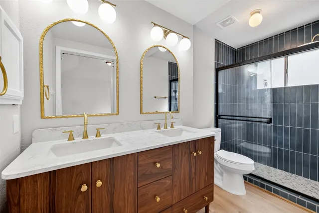 a bathroom with a double vanity sink toilet and shower