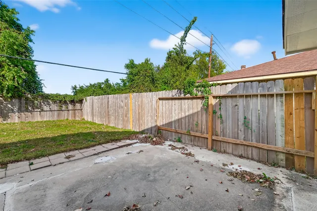 a backyard of a house with plants and trees with wooden fence