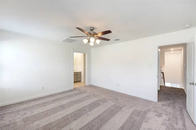 a view of an empty room with chandelier fan